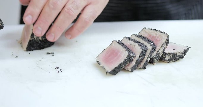 Chef sta tagliando tonno con sesamo nero su un tagliere di un ristorante
