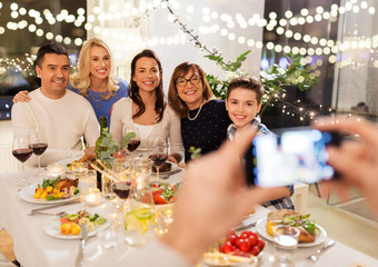 celebration, holidays and people concept - happy family having dinner party at home and photographing by smartphone