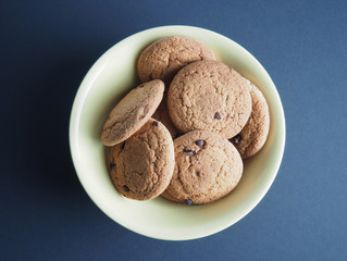 tasty oatmeal cookies in a yellow ceramic bowl on a dark paper background