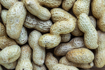 Unshelled brown peanuts background, top view