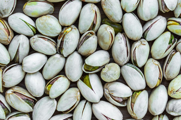 Background in the form of inshell pistachios on a dark surface, top view