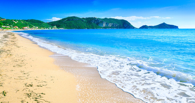 Beautiful summertime panoramic seascape. Awesome view picturesque green slopes coastline sea and golden sand beach shore in the crystal clear azure water sea bay. Afionas. Corfu. Greece.