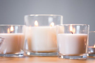 decoration, hygge and cosiness concept - burning white fragrance candles on wooden table