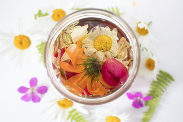 glass bottle oil based on various medicinal herbs and flowers, cosmetic oil for skin care on white background