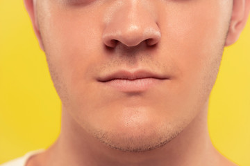 Caucasian young man's close up portrait on yellow studio background. Beautiful male model with well-kept skin. Concept of human emotions, facial expression, sales, ad. Lips and cheeks, calm.