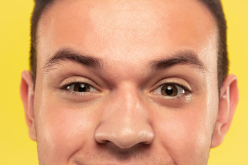 Obraz premium Caucasian young man's close up portrait on yellow studio background. Beautiful male model with well-kept skin. Concept of human emotions, facial expression, sales, ad. Eyes looking at camera.