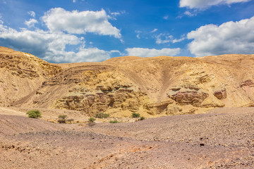 Middle East world heritage Judean desert nature scenery landscape view of sand stone wasteland foreground and rocky mountain background with blue sky white clouds 