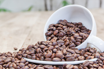 Coffee beans in a white ceramic cup on old wooden table