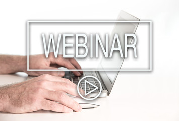 close-up of text webinar and play button against hands of person working on laptop computer, e-learning concept