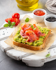 Toast with avocado, red fish (salmon, trout), caviar and black sesame. Tasty, bright, delicious healthy breakfast or lunch