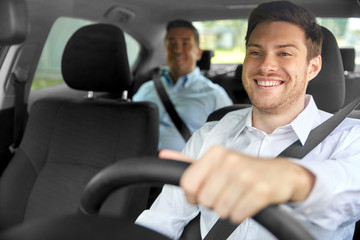 transport, vehicle and taxi concept - happy smiling male driver driving car with passenger