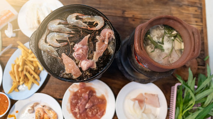 Top view of shrimp and pork on top of pan and clay pot. Food around in pan pork restaurant.