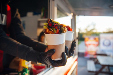 delicious Viennese waffles with fruits chocolate and syrup in a girl's hands in a paper cup, a treat for children and adults