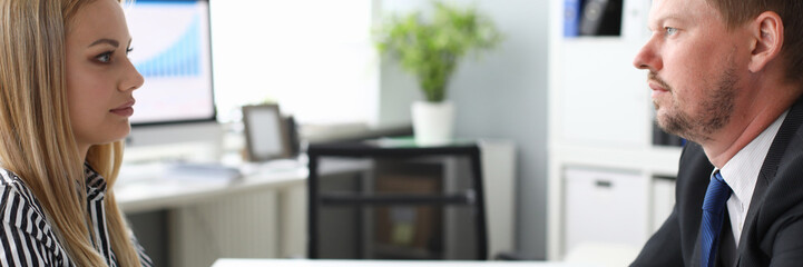 Portrait of people sitting opposite of each other and discussing terms of important business contract or agreement. Modern office interior. Blurred background