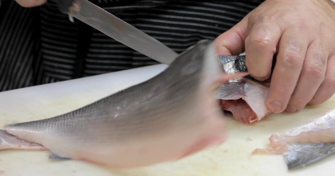 Sfilettare un pesce su un tagliere bianco