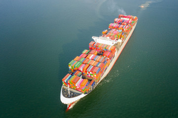 Aerial view of the large volume of TEU container on ship sailing to the sea carriage the shipment from loading port to destination.