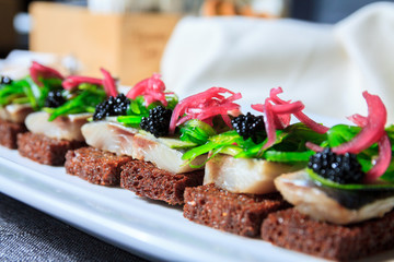 Cook prepares appitizers in the restaurant kitchen. Tasty appetizer with black caviar and cucumber on plate.