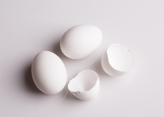 Chicken white eggs. Chicken eggs close-up. Two whole chicken eggs and one broken. An empty broken egg. Conceptual shot.