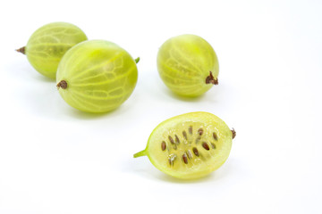 Heap of gooseberries, one halved on white background, copy space