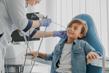 Mid adult female doctor checking patients ear during medical examination