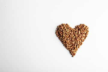 healthy food. Heart shape made from buckwheat grains on white background. Top view. copy space