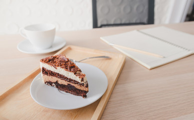 Delicious chocolate cakes on the table. Wood desk in home office and notebook.