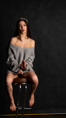 Fototapeta na wymiar beautiful sexy girl, posing a short gray dress, black background chair