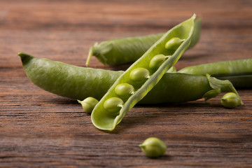 Peas close-up. Green pea pods on a wooden table surface.