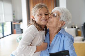 Obraz premium Great grandmother giving a kiss to little girl