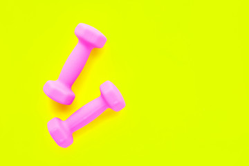 Pink dumbbells isolated on yellow background. Copy space