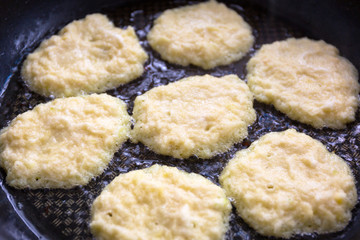 Raw hash browns fried on a pan