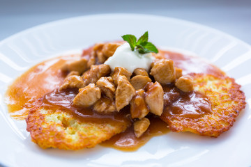 Tasty dinner on a plate of hash browns with sauce and chicken