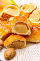 Fresh baked Dutch filled spicy cookies from puff pastry with almonds in autumn colors on dark wooden background