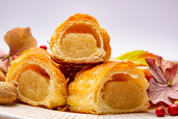 Fresh baked Dutch filled spicy cookies from puff pastry with almonds in autumn colors on dark wooden background