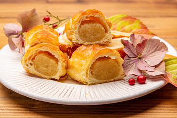 Fresh baked Dutch filled spicy cookies from puff pastry with almonds in autumn colors on dark wooden background