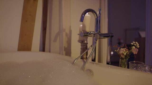 water and foam filled bathtub in a candlelit upscale hotel suite - Eine mit Badewasser uns Schaum gef&uuml;llte Badewanne in einer mit Kerzenlicht beleuchteten Hotelsuite 4K ProRes Footage