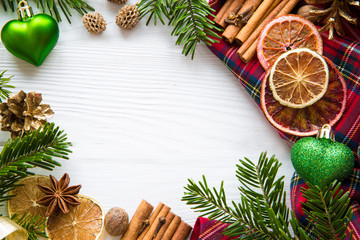 Christmas background, aromatic dried oranges, cinnamon sticks and anise spices, green heart shape christmas decoration, space for text, top view. 