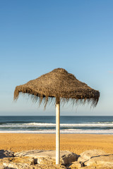 Empty beach with an sun umbrella on the rocks