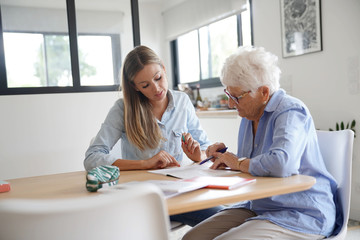 Homehelp assisting elderly woman with paperwork