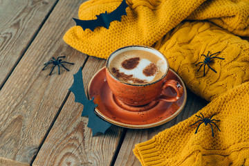 Halloween holiday background with coffee cup and autumn sweater on wooden table