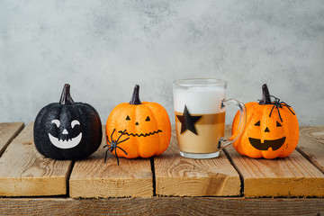 Halloween holiday concept with latte macchiato coffee cup and jack o lantern glitter pumpkin decor...