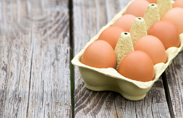 Fresh eggs in carton box on a wooden table with copy space