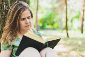 Obraz premium Young woman reading a book outdoors