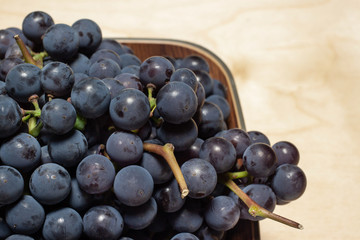 Bunch of blue grapes on plate with wooden background