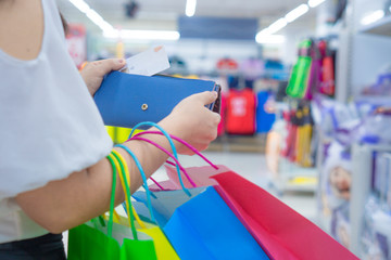 Close up woman hand holding purse, shopping bag and credit card in the shopping mall. Shopping concept.