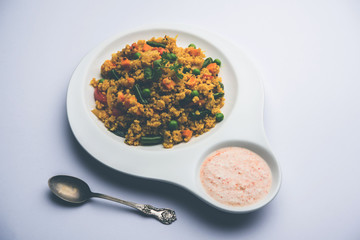 Broken wheat or Daliya Upma, served in a bowl. selective focus