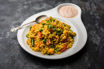 Broken wheat or Daliya Upma, served in a bowl. selective focus