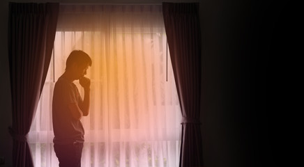 Alone man silhouette standing at the window closed with curtains in bedroom. Man stands at window alone, Depression and anxiety disorder concept. copy space background for text