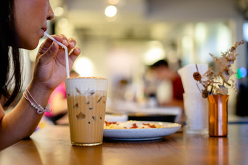 Beautiful young woman enjoying latte coffee in cafe, Woman sucks ice coffee with milk.