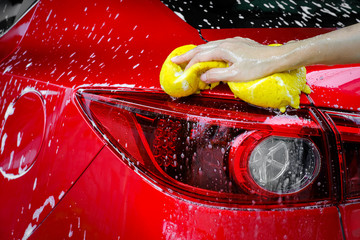 Cleaning automobile with sponge at red car wash